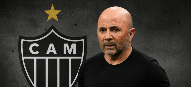 Jorge Sampaoli em frente ao escudo do Atlético Mineiro com expressão séria.