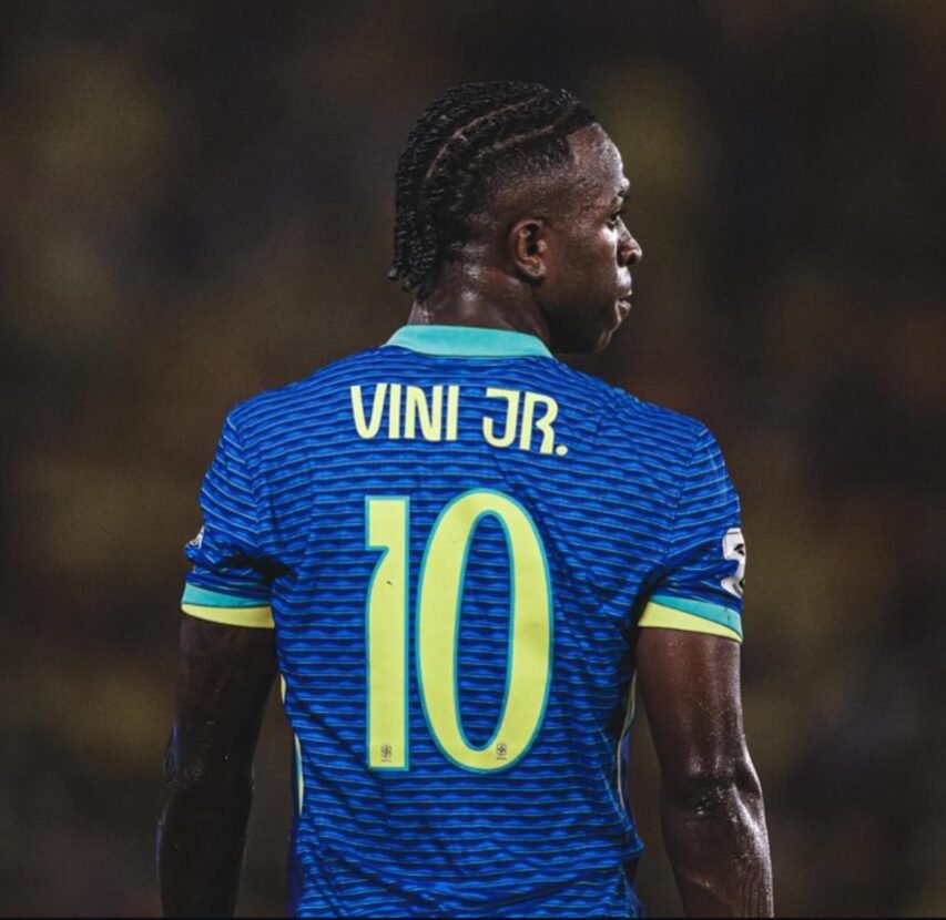 Jogador visto de costas no gramado, camisa azul listrada com número 10; luzes do estádio ao fundo. Título: No gramado, o número 10