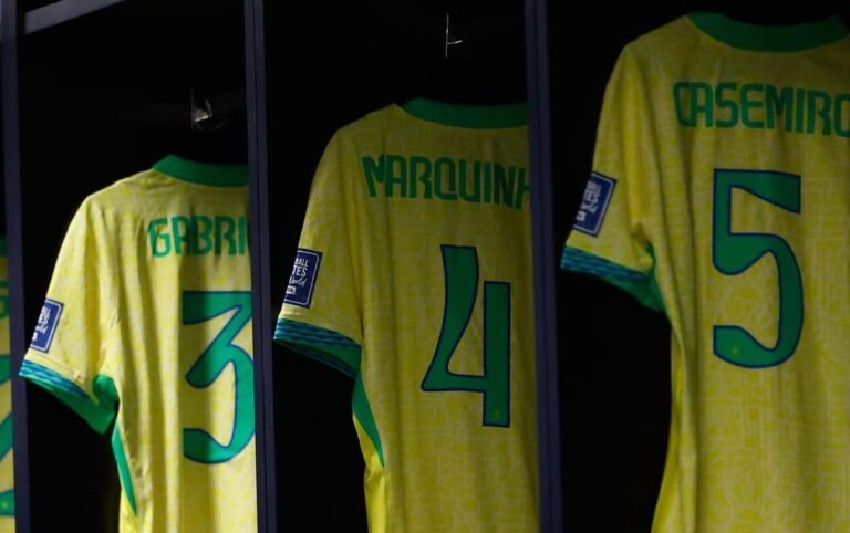 Camisas da Seleção Brasileira penduradas no vestiário, com os nomes Gabriel, Marquinhos e Casemiro visíveis, preparadas para uma partida.