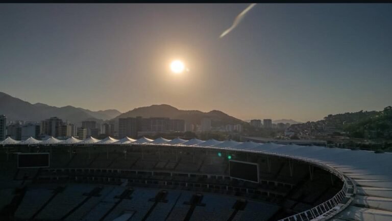 brilhando forte no céu, montanhas e prédios da cidade do Rio de Janeiro ao fundo.