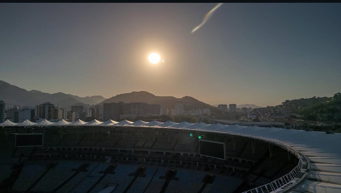 brilhando forte no céu, montanhas e prédios da cidade do Rio de Janeiro ao fundo.